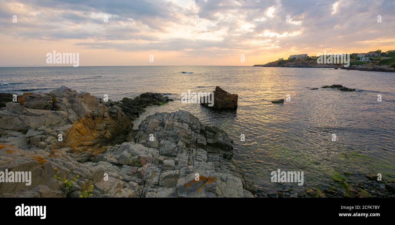 Sonnenuntergang an der Küste des schwarzen Meeres. Wunderbare dramatische Landschaft mit Felsen auf dem Kiesstrand unter einem bewölkten Himmel. Samt Saison Urlaub Stockfoto