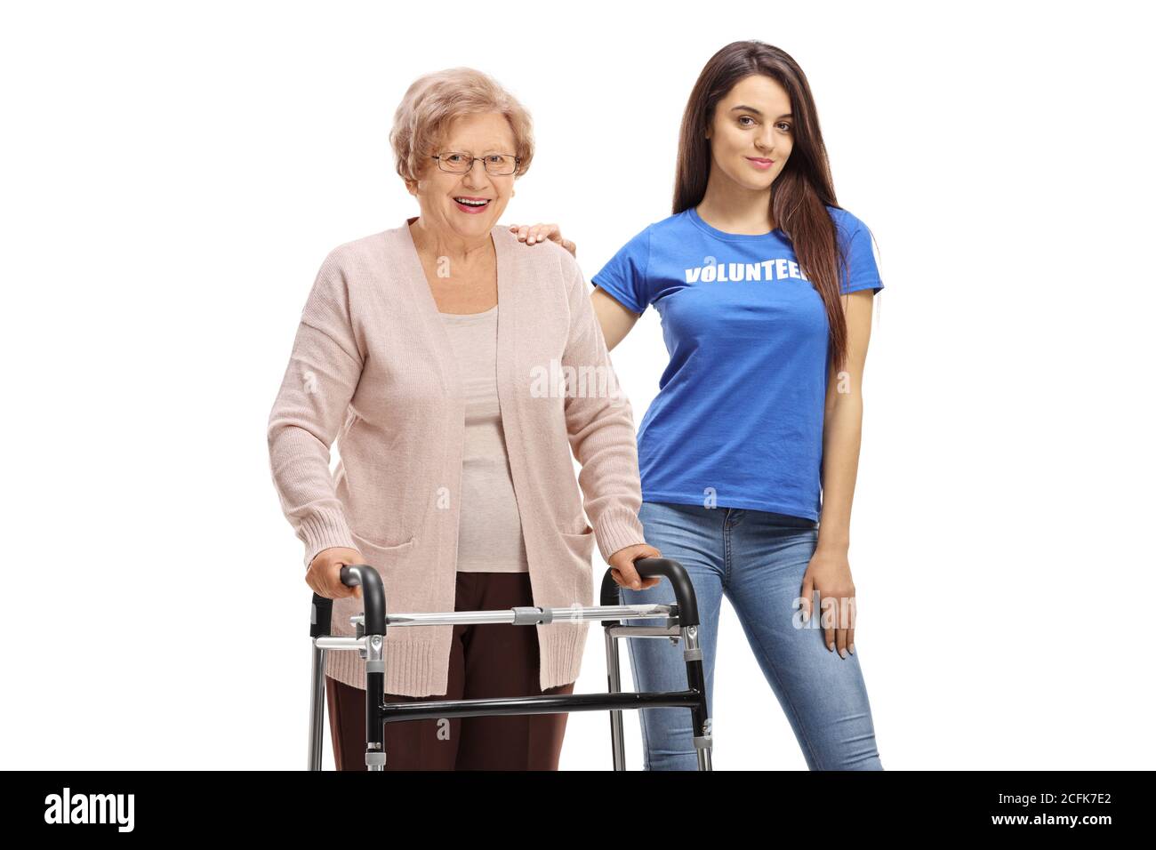 In voller Länge Porträt einer älteren Frau mit einem Walker stehen mit einer jungen Frau freiwillig auf weißem Hintergrund Stockfoto