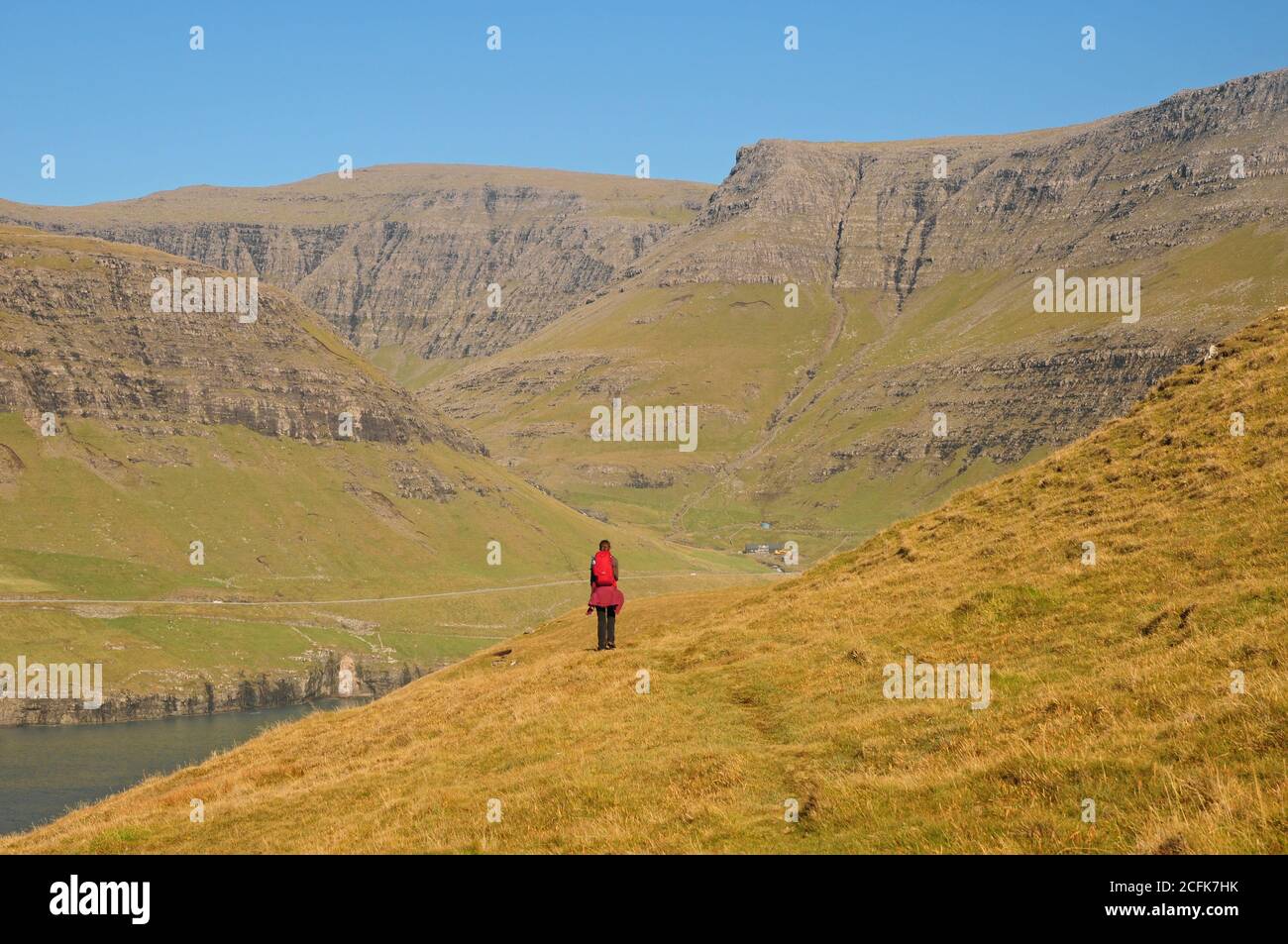 Eine alleinreisende Frau, die auf den Färöern entlang der Fjorde von Vagar wandert. Stockfoto