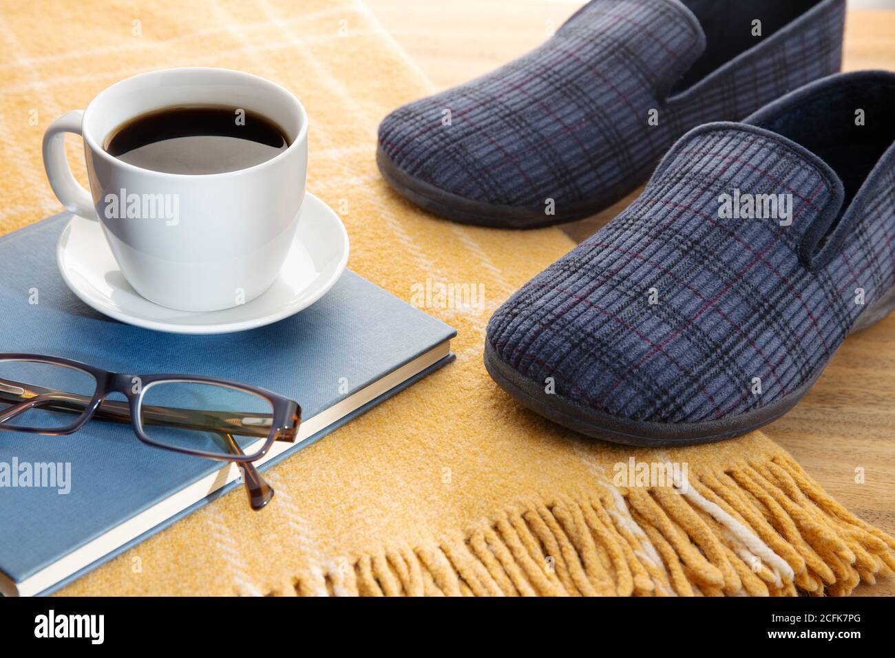 Hausschuhen für Männer, Kaffee, Buch und Wolldecke. Home Entspannung im Winter Konzept Stockfoto