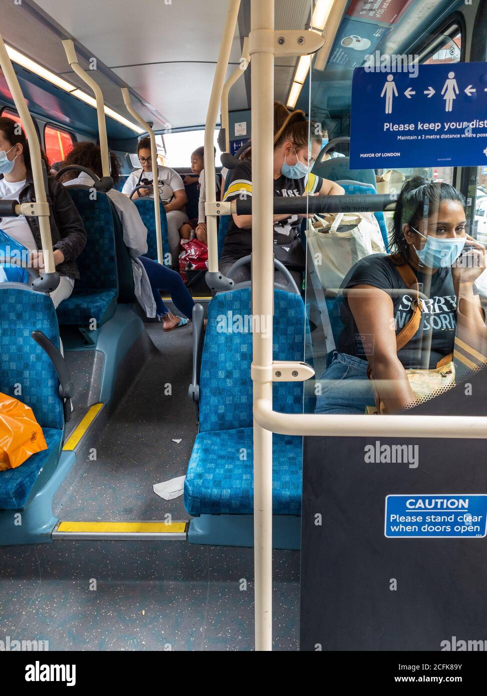 Fahrgäste in einem Bus tragen Gesichtsbezüge und versuchen, soziale Distanzierung nach Regierung Covid-19 Sicherheitsregeln für den öffentlichen Verkehr zu üben. Stockfoto