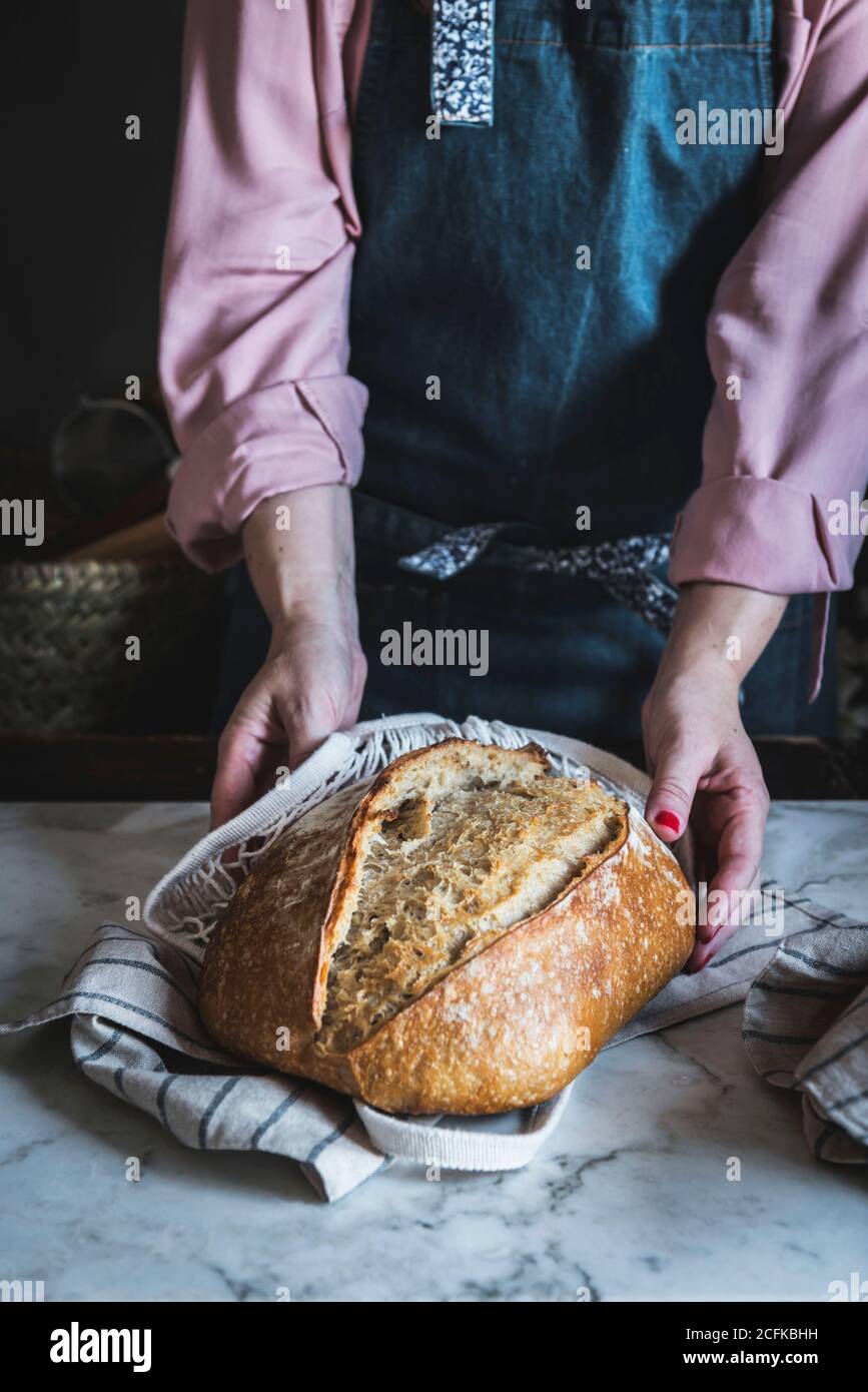 Nahaufnahme einer Frau, die mit ihren Händen einen Laib Brot in der Hand hält Stockfoto