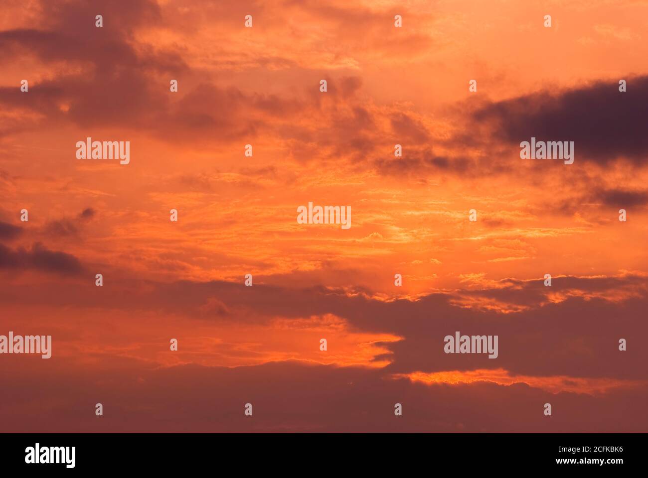 Feuerhimmel Hintergrund. Weiche Wolken mit dem Hauch der Sonne bei Sonnenuntergang. Viele Orange Töne und Muster von Wolken. Stockfoto