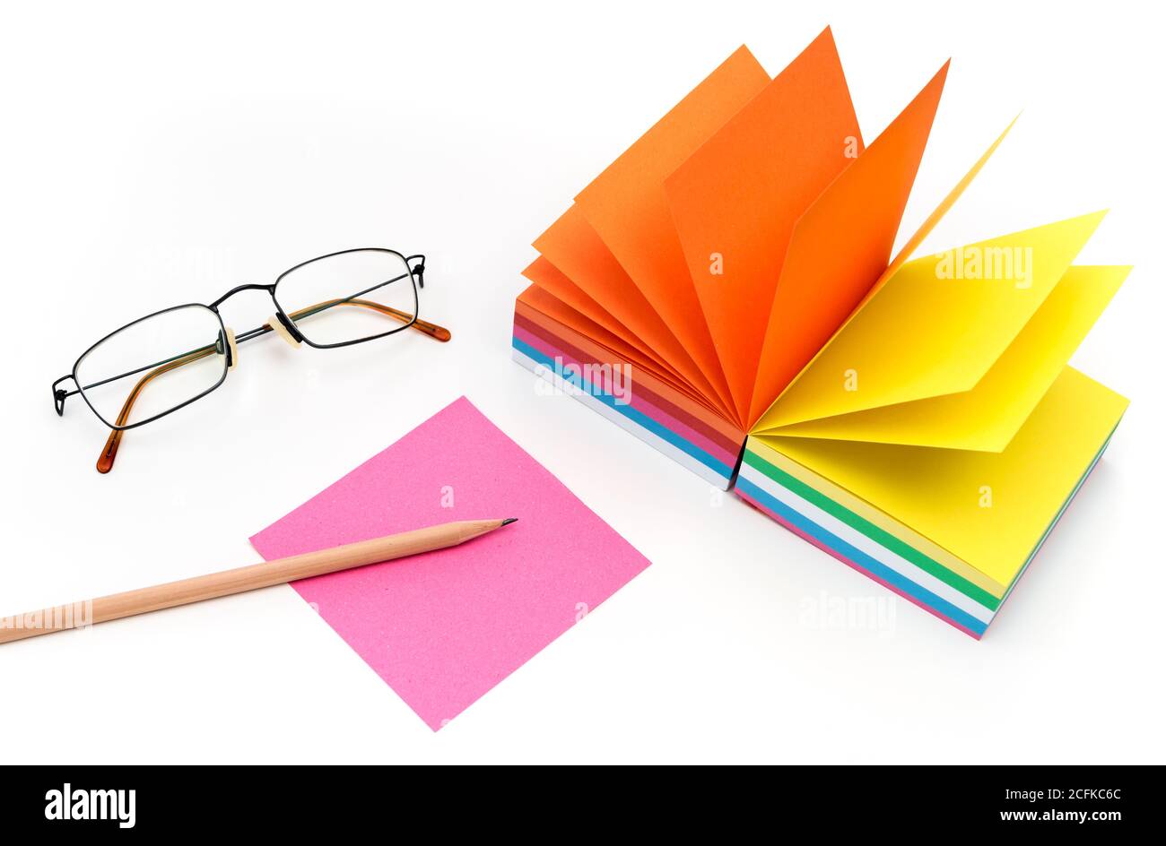Bunte Papierauflage für Notizen, Bleistift und Gläser auf weißem Tisch, Draufsicht. Stockfoto