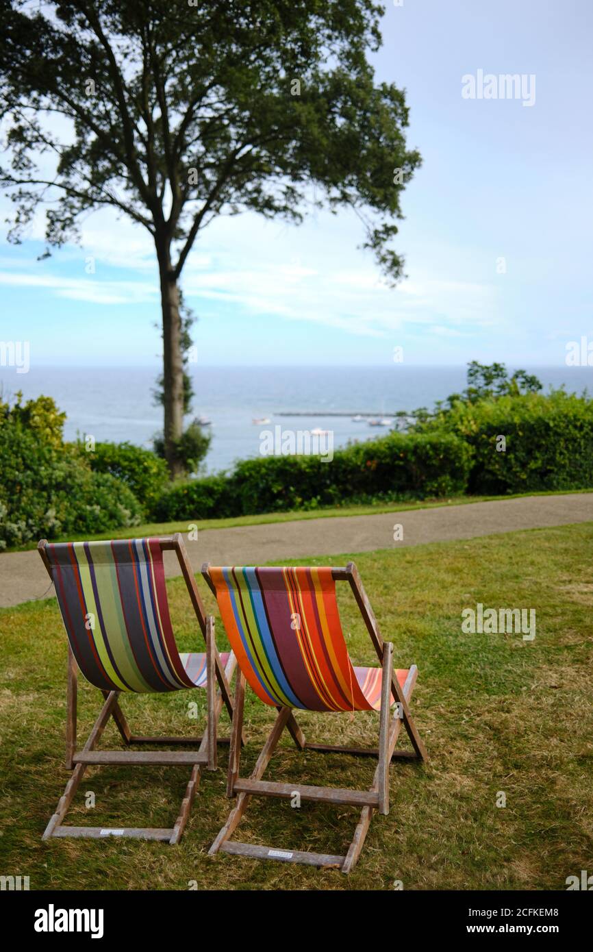 Zwei Liegestühle sitzen auf einem grünen Rasen mit Blick auf das Meer in der Nähe von Lyme Regis, Dorset. VEREINIGTES KÖNIGREICH Stockfoto