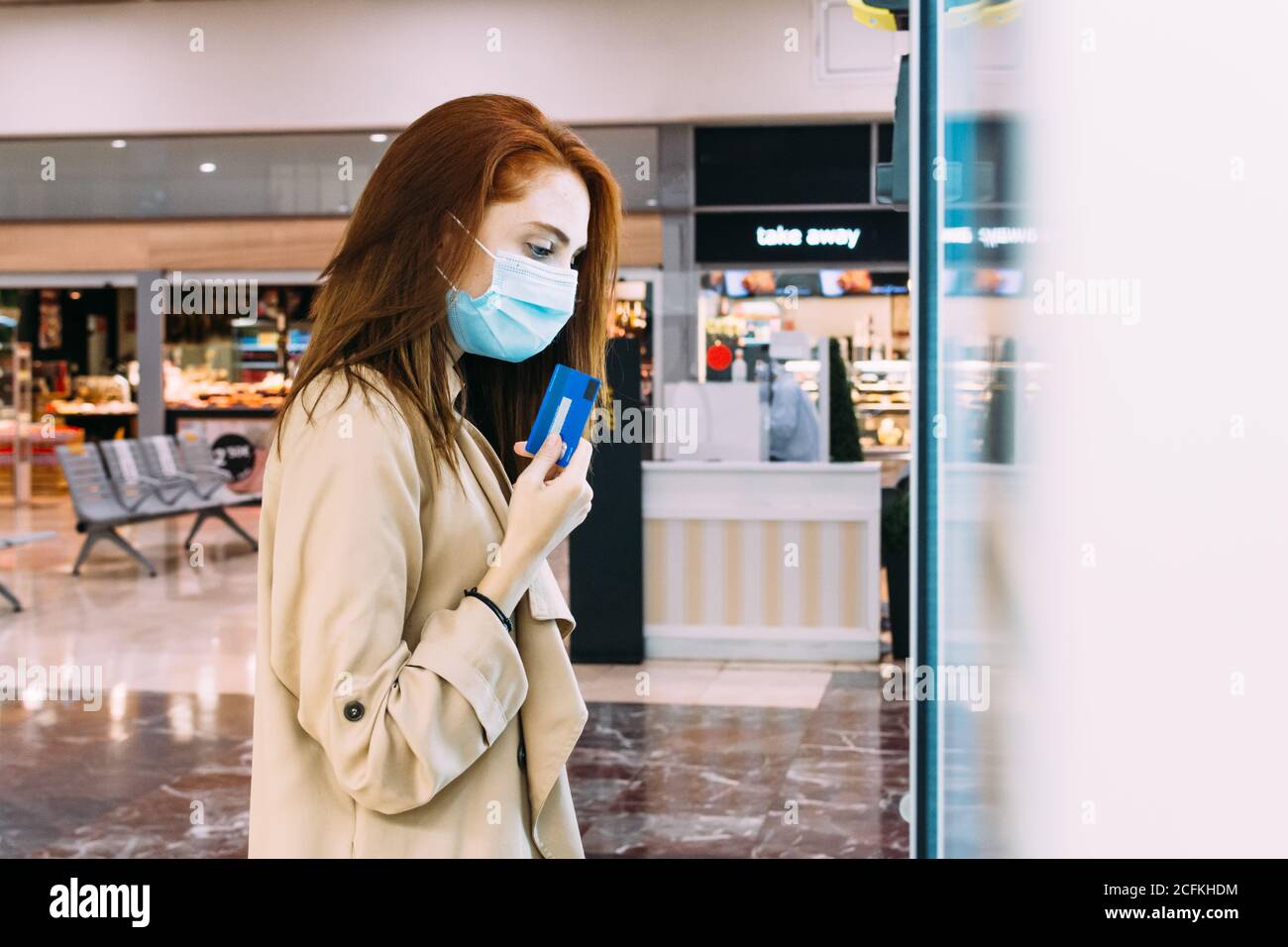 Frau mit Gesichtsmaske verwendet ihre Kreditkarte Zahlen Sie am Automaten Stockfoto