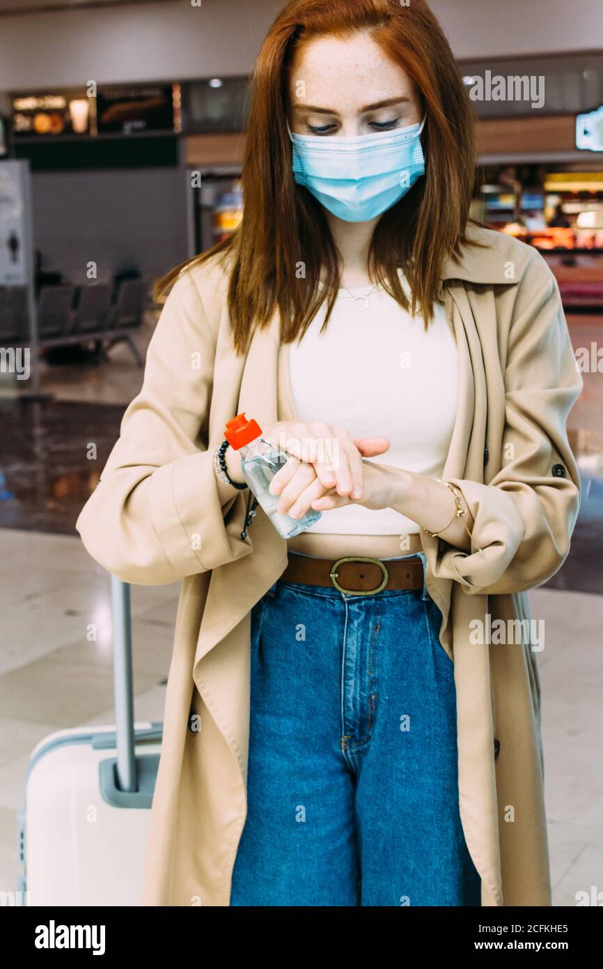 Eine Frau, die eine Gesichtsmaske trägt und Hydro-alkoholisches Gel verwendet Um ihre Hände am Bahnhof zu desinfizieren Stockfoto