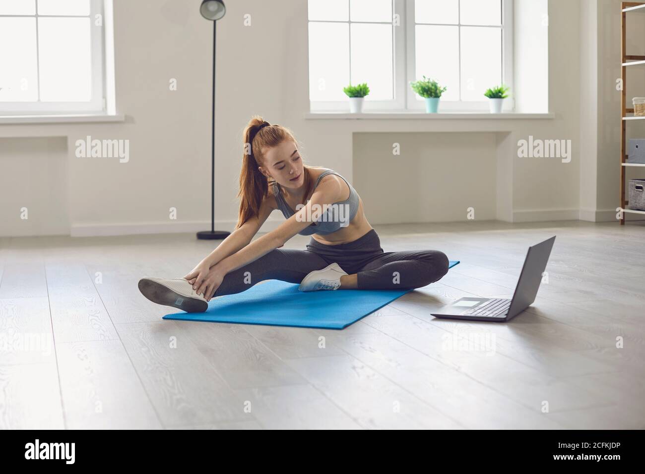 Mädchen tun Stretching-Training mit Video während Online-Unterricht bei Zu Hause Stockfoto