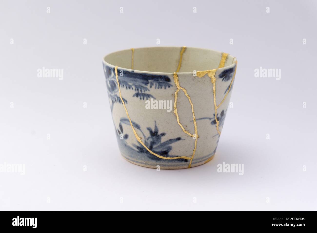 Kintsugi weiß und blau Soba Tasse. Gold Risse Restaurierung auf alten japanischen Keramik. Stockfoto
