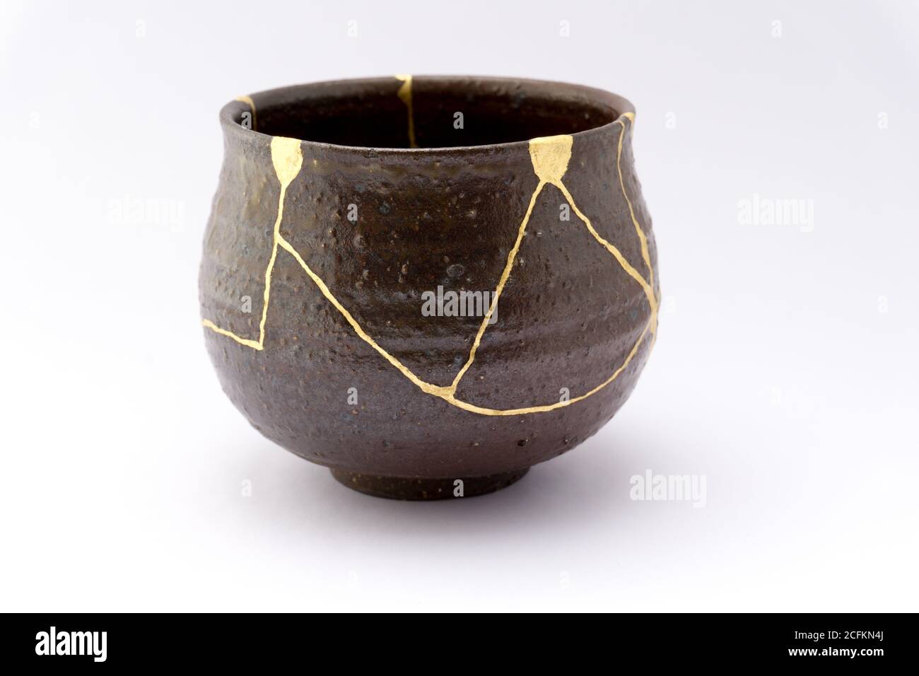Kintsugi schwarzer Tee Zeremonie Schüssel. Gold Risse Restaurierung auf alten japanischen Keramik. Stockfoto