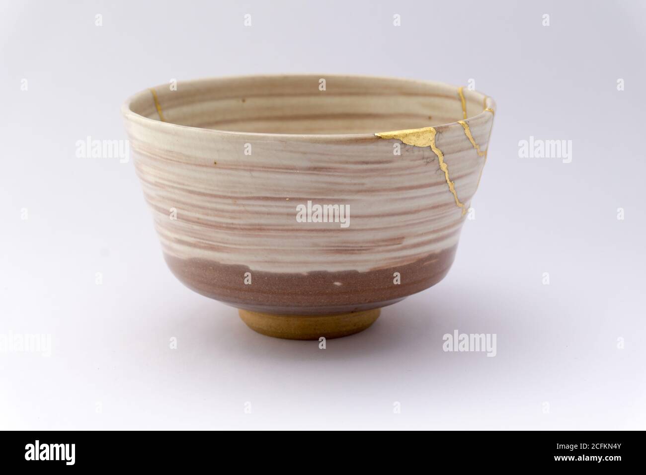 Kintsugi beige Tee Zeremonie Schüssel. Gold Risse Restaurierung auf alten japanischen Keramik. Stockfoto