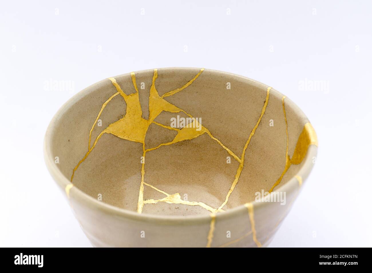 Kintsugi beige Tee Zeremonie Schüssel. Gold Risse Restaurierung auf alten japanischen Keramik. Stockfoto