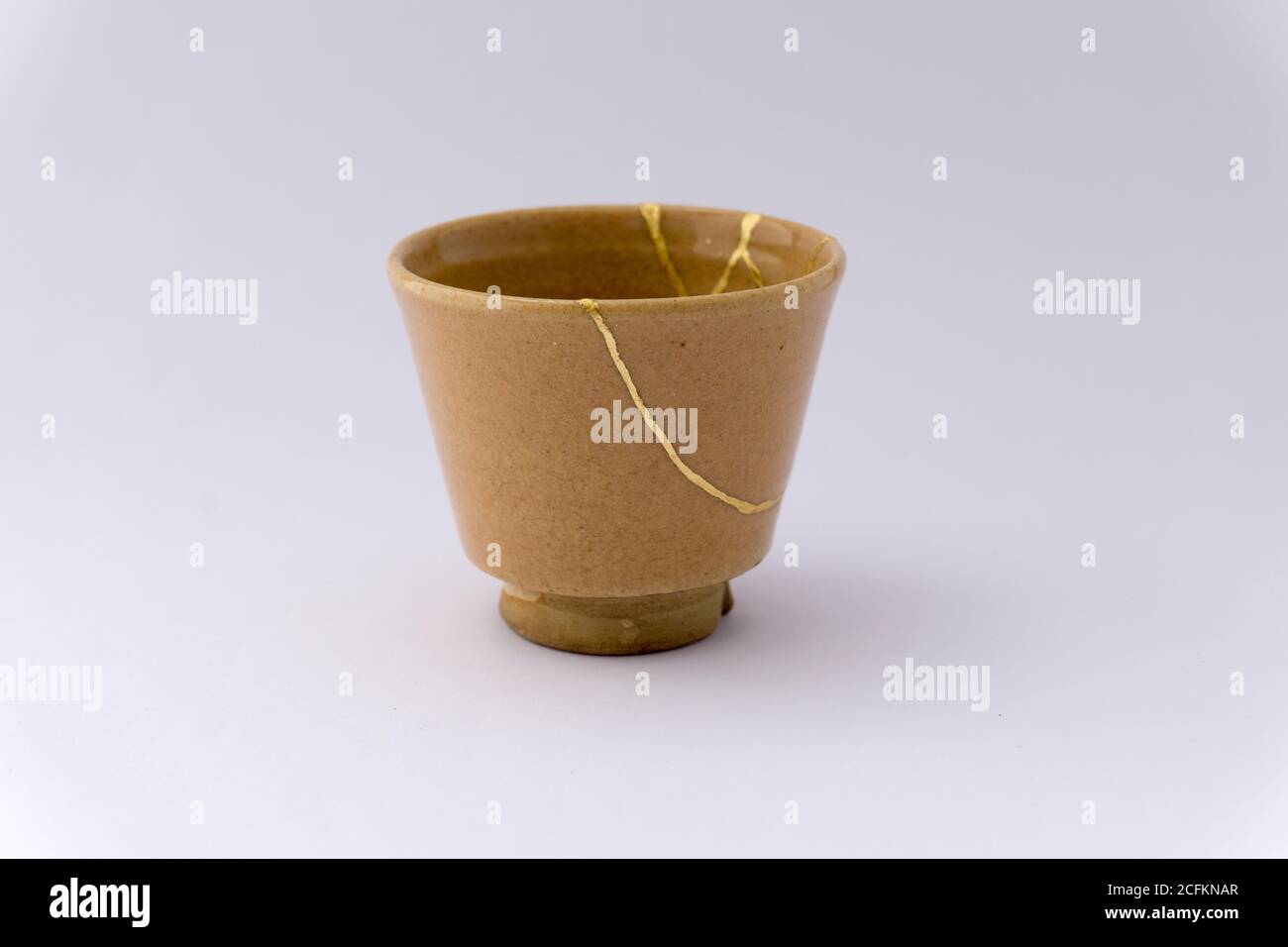 Tintsugi beige Sake Tasse. Gold Risse Restaurierung auf alten japanischen Keramik. Stockfoto