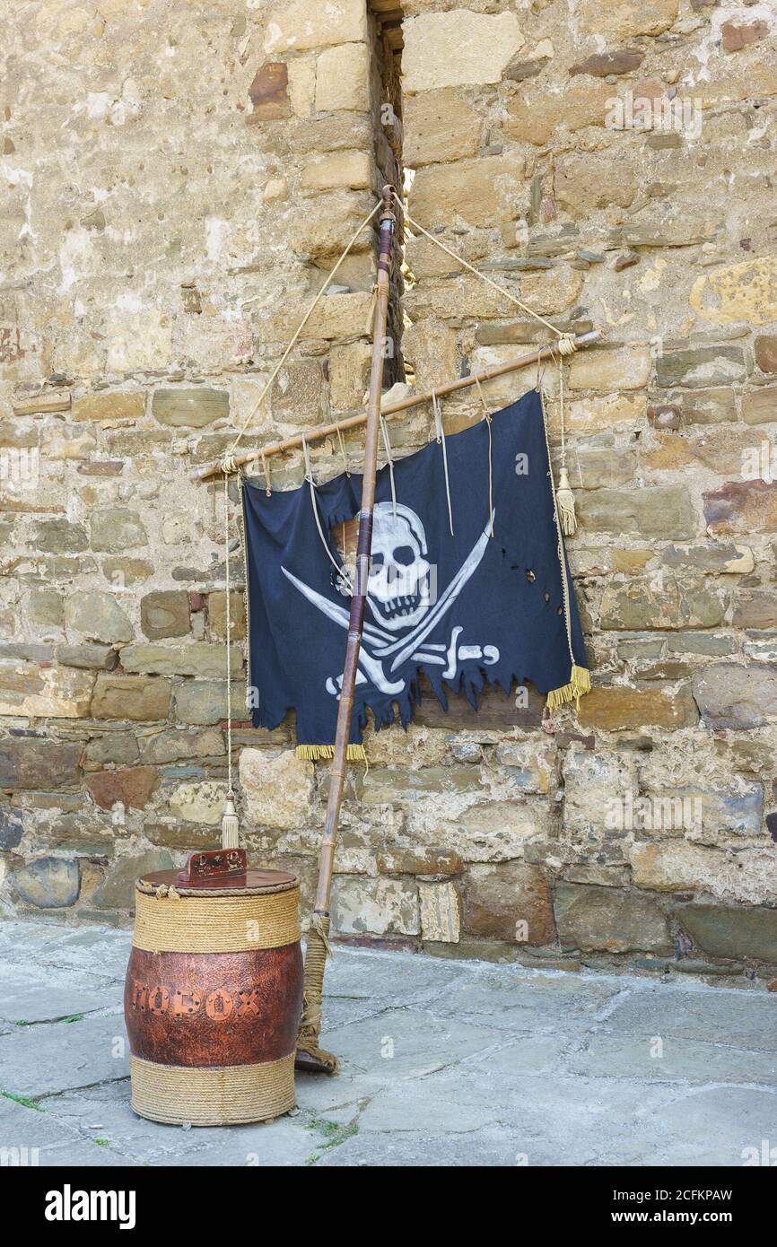 Pirate-Attribute. Ein Fass Schießpulver und eine Flagge mit dem Jolly Roger Stockfoto