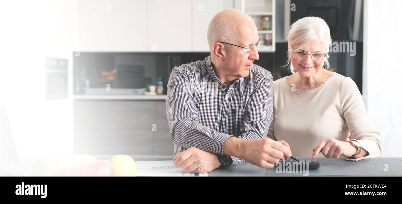 Seniorenpaar berechnet gemeinsam das Budget. Rentner zahlen die Rechnungen. Web-Banner-Bild Hintergrund mit Kopierplatz. Stockfoto