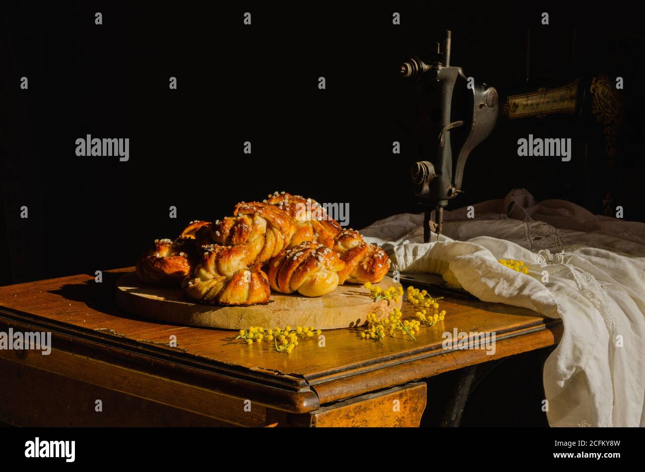 Stapel köstlicher schwedischer Kardamombrötchen auf Schneidebrett gelegt Auf rustikalem Tisch mit Nähmaschine Stockfoto