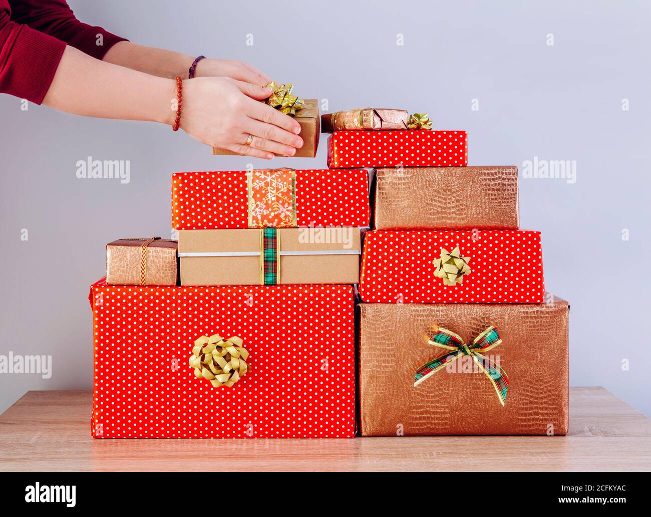 Detailansicht der Frau Person Hände stapeln Weihnachtsgeschenke in einem Stapel. Vorbereitung für Weihnachten Konzept. Stockfoto