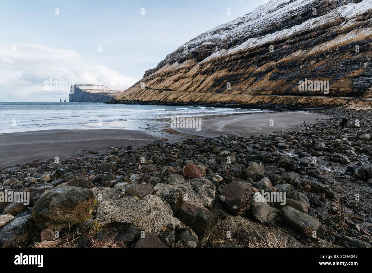Majestätische Landschaft von felsigen Gelände mit Schnee in der Nähe Ruhe bedeckt Meer an bewölktem Tag auf den Färöern Stockfoto