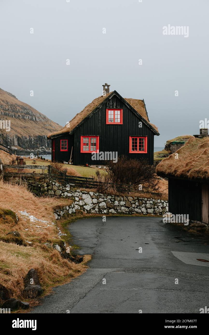 Holzhaus in Siedlung im Herbst auf den Färöern Auf verschneiten Bergen Stockfoto