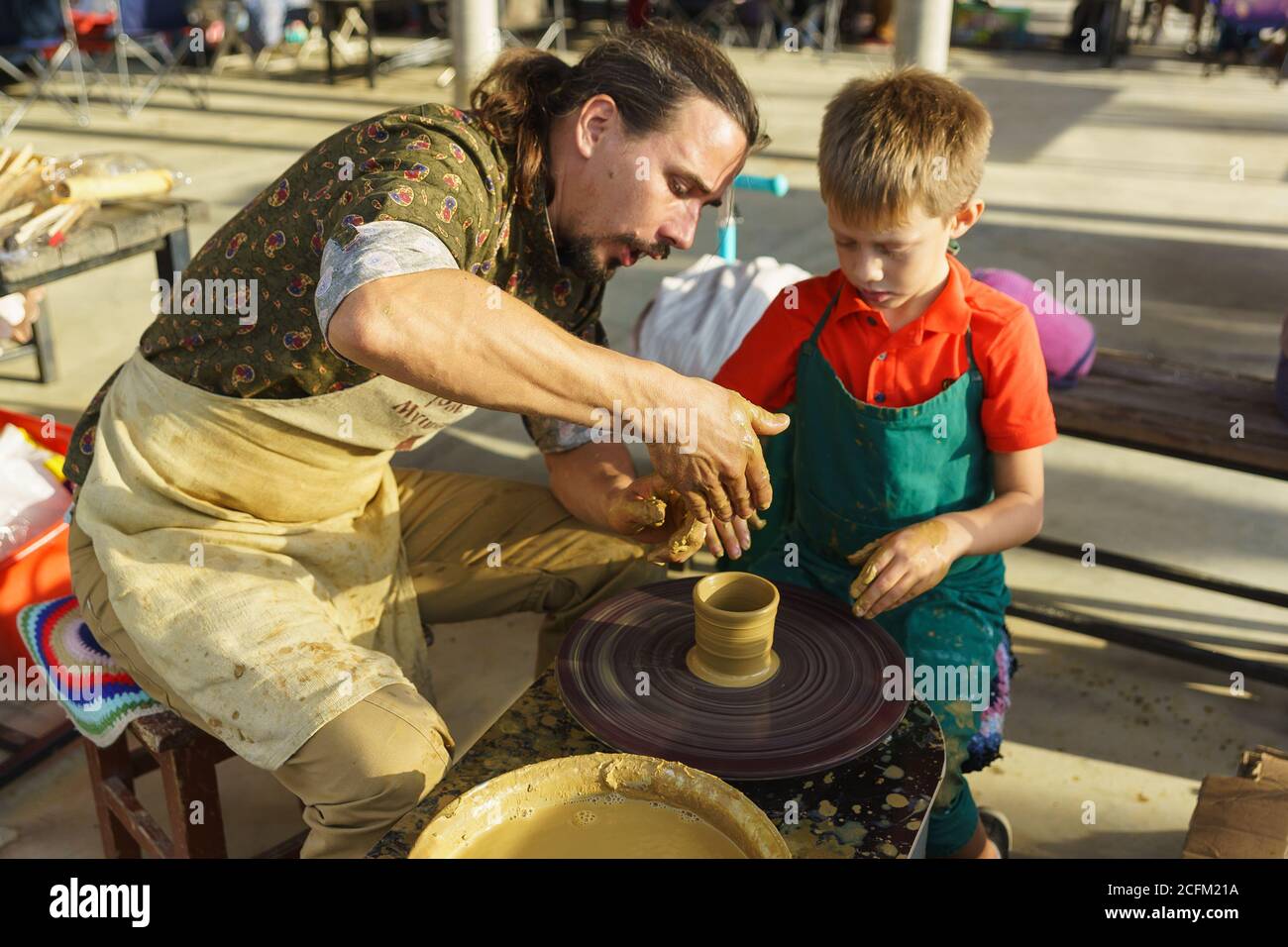 Moldawisch, Krymsk, Russland-05. Oktober 2019: Meister lehrt Jungen Keramik aus Ton zu machen. Rotierendes Töpferrad. Selektiver Fokus auf Hände Stockfoto