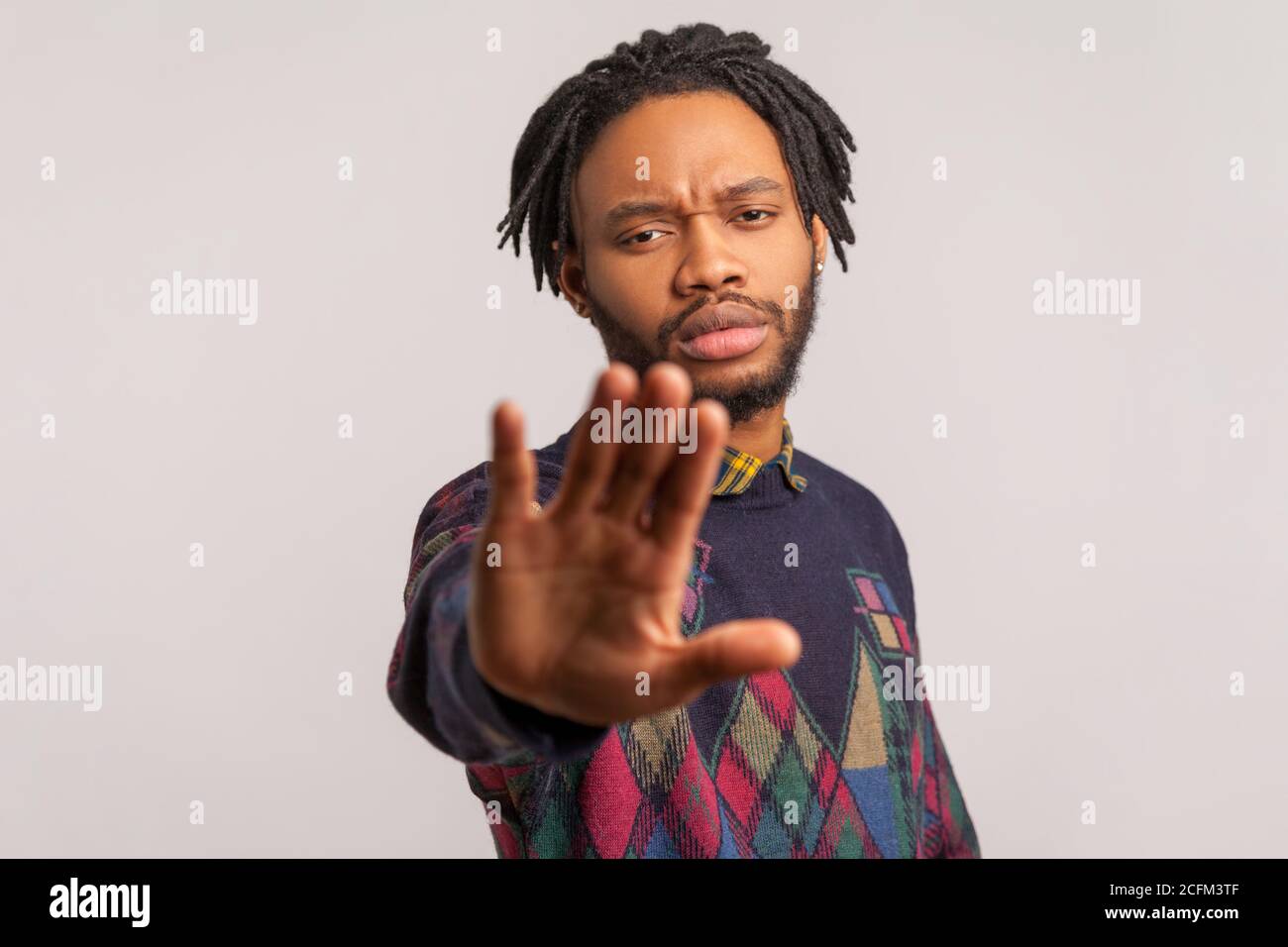 Halt! Nahaufnahme ernsthaft besorgt afrikanischen Mann mit Dreadlocks Strecke seine Hand nach vorne zeigt keine Geste, Warnung, stoppen Rassismus. Innenaufnahme des Studios i Stockfoto