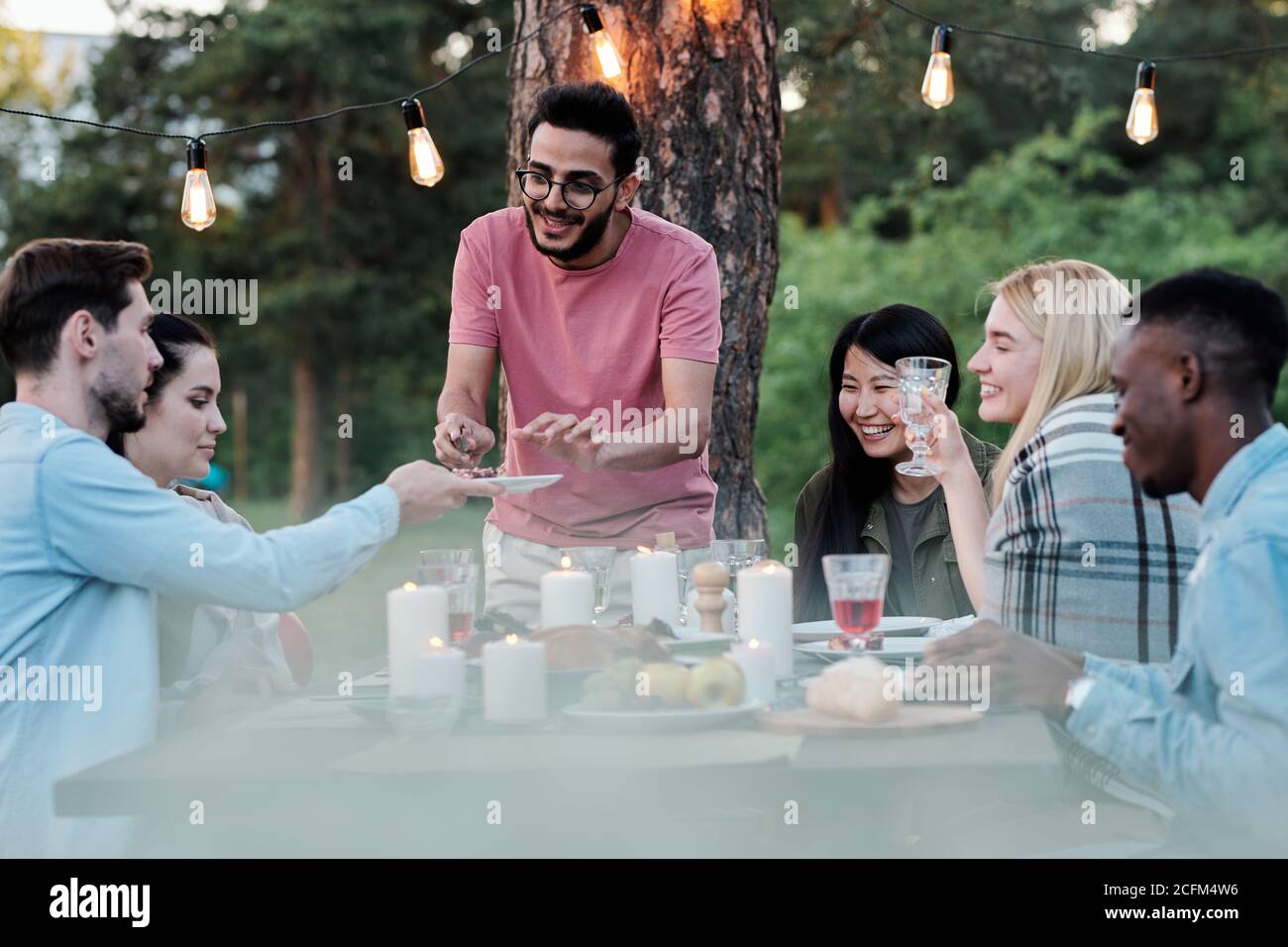 Junger lächelnder Mann gemischter Ethnie, der leckeres Essen nimmt Platte Stockfoto