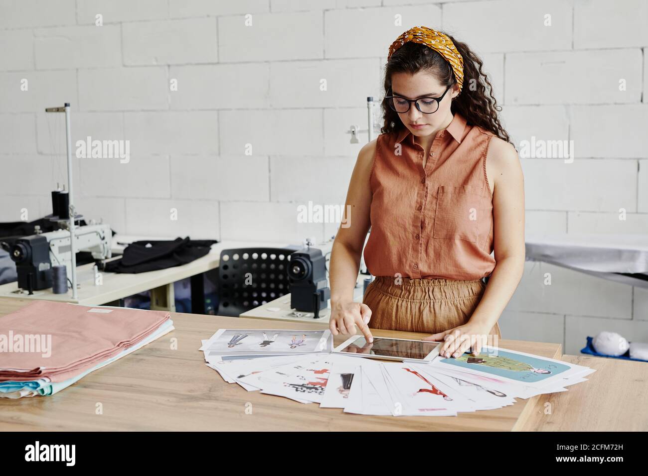 Hübsche junge Modedesignerin mit Touchpad Scrollen durch neue Modelle Stockfoto