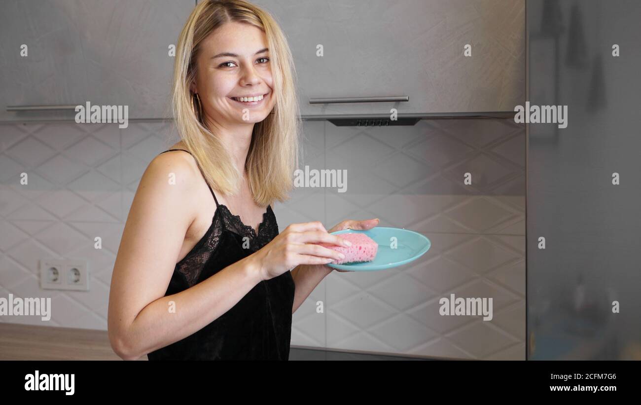 Junge Frau, die Geschirr in der modernen Küche waschen Stockfoto