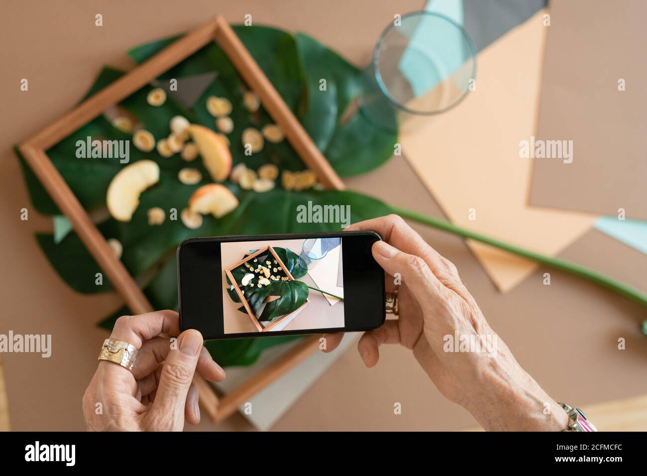 Hände der kreativen reifen Frau mit Smartphone, das Foto von Zusammensetzung Stockfoto