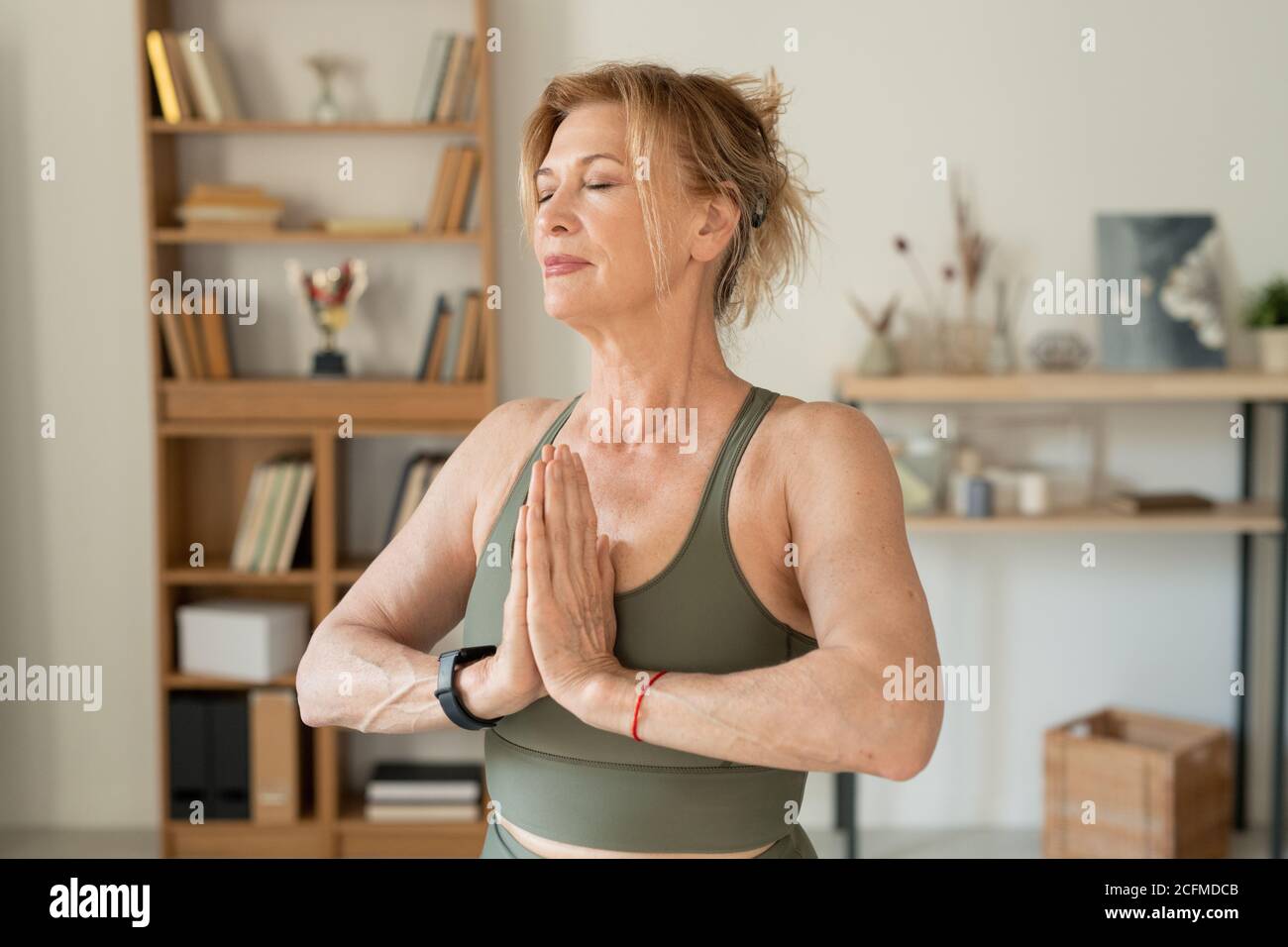 Entspannte reife Frau in Sportswear halten ihre Hände zusammen Nach Brust Stockfoto