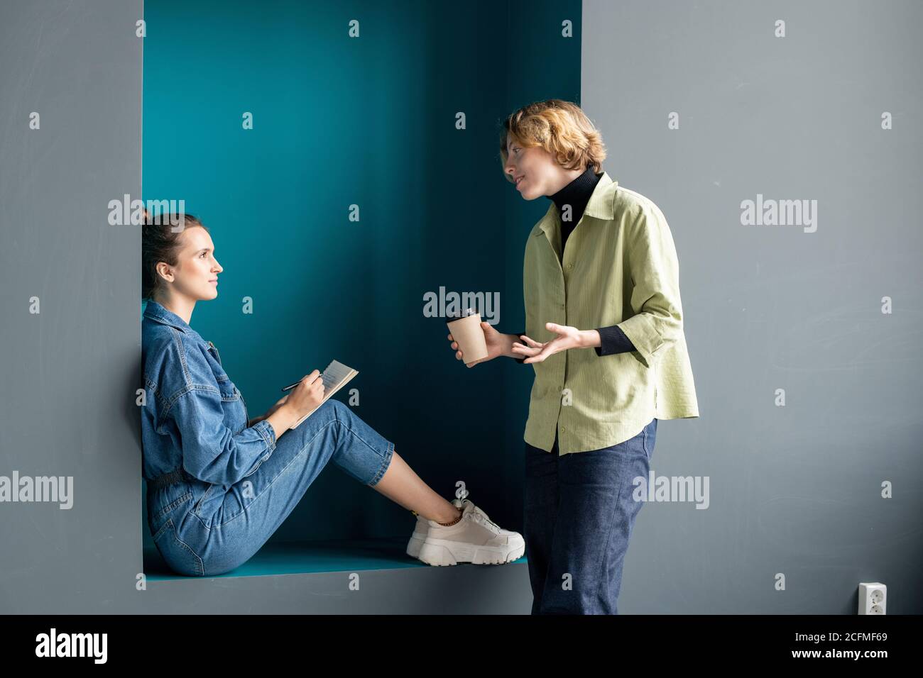 Zwei moderne junge Geschäftsfrauen in Casualwear diskutieren über die Arbeit im Büro Stockfoto