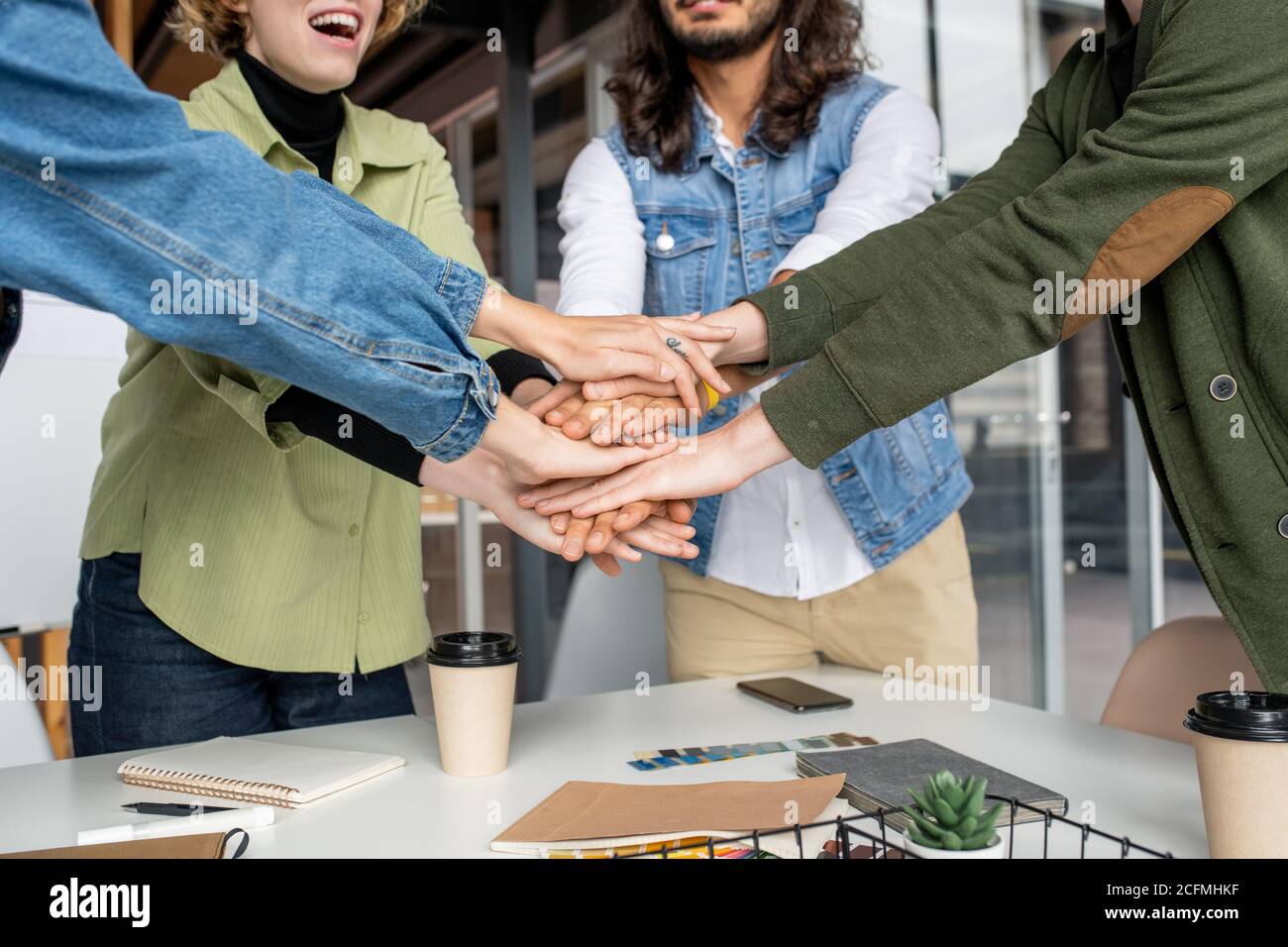 Glückliche junge kreative Designer oder Software-Entwickler machen Haufen von Hände Stockfoto