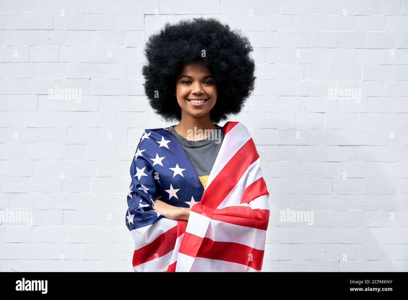 Glückliche afrikanische Frau stehen auf weißem Hintergrund eingewickelt in USA Flagge, Porträt. Stockfoto