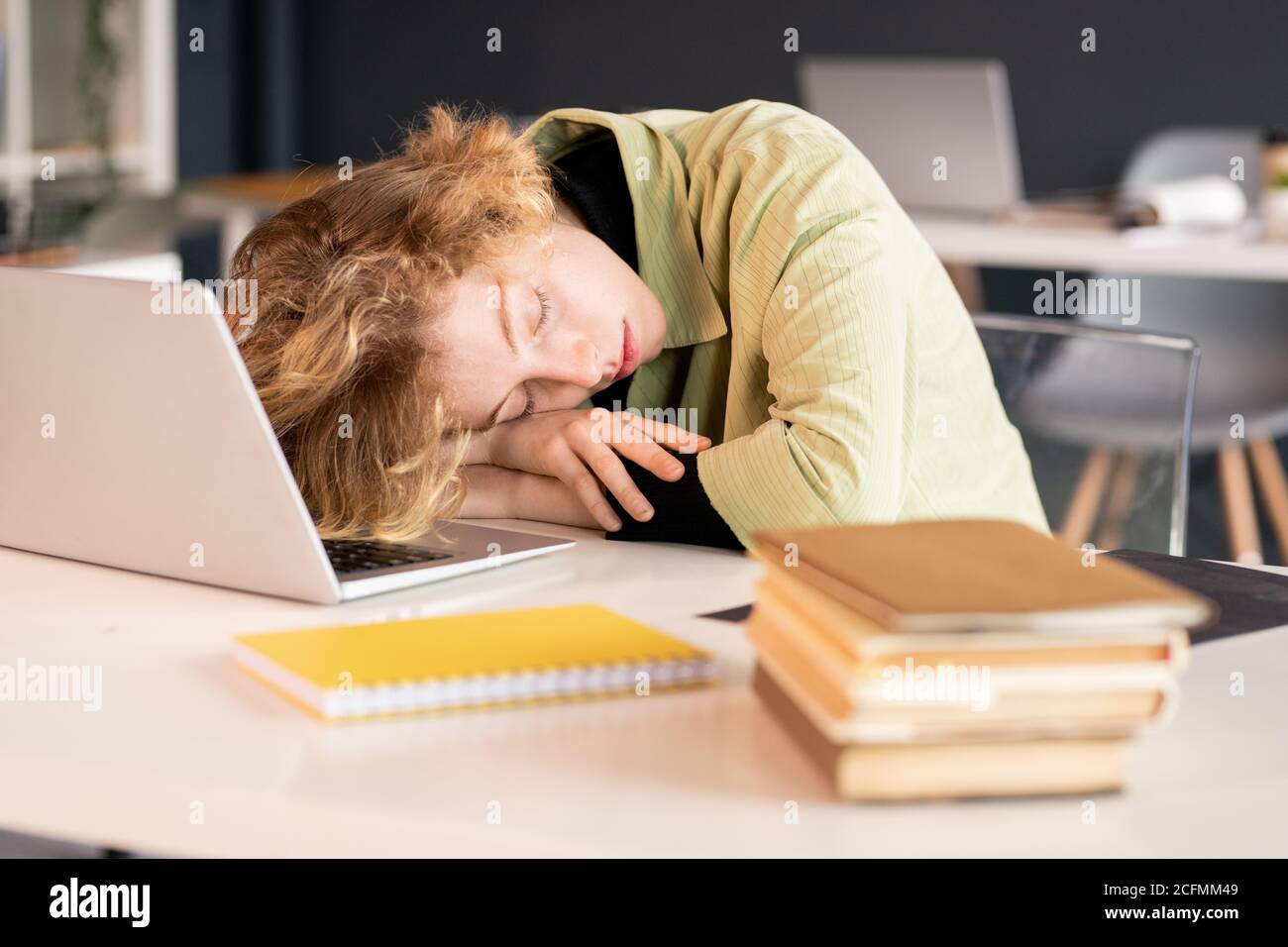 Junge erschöpfte Studentin oder Büromanagerin, die den Kopf aufrecht hält Hände Stockfoto