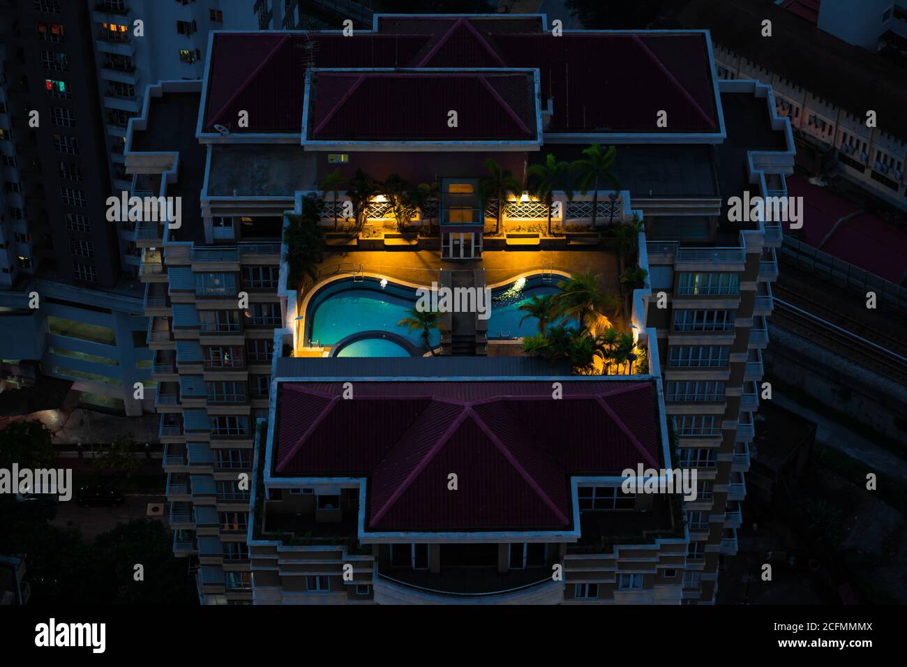 Nachts Blick von oben auf eine mehrstöckige Wohnanlage mit einem Pool auf dem Dach. Stockfoto