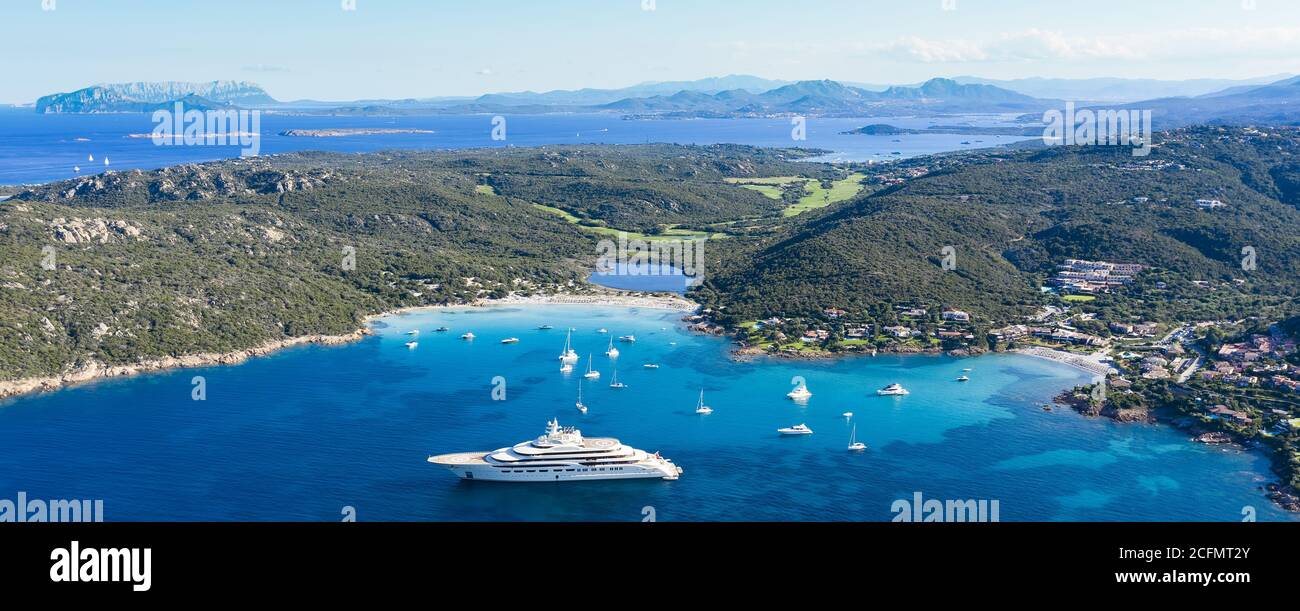 Blick von oben, herrlicher Panoramablick auf den Grande Pevero Strand mit Booten und Luxusyachten, die auf einem türkisfarbenen, klaren Wasser segeln. Sardinien, Italien. Stockfoto