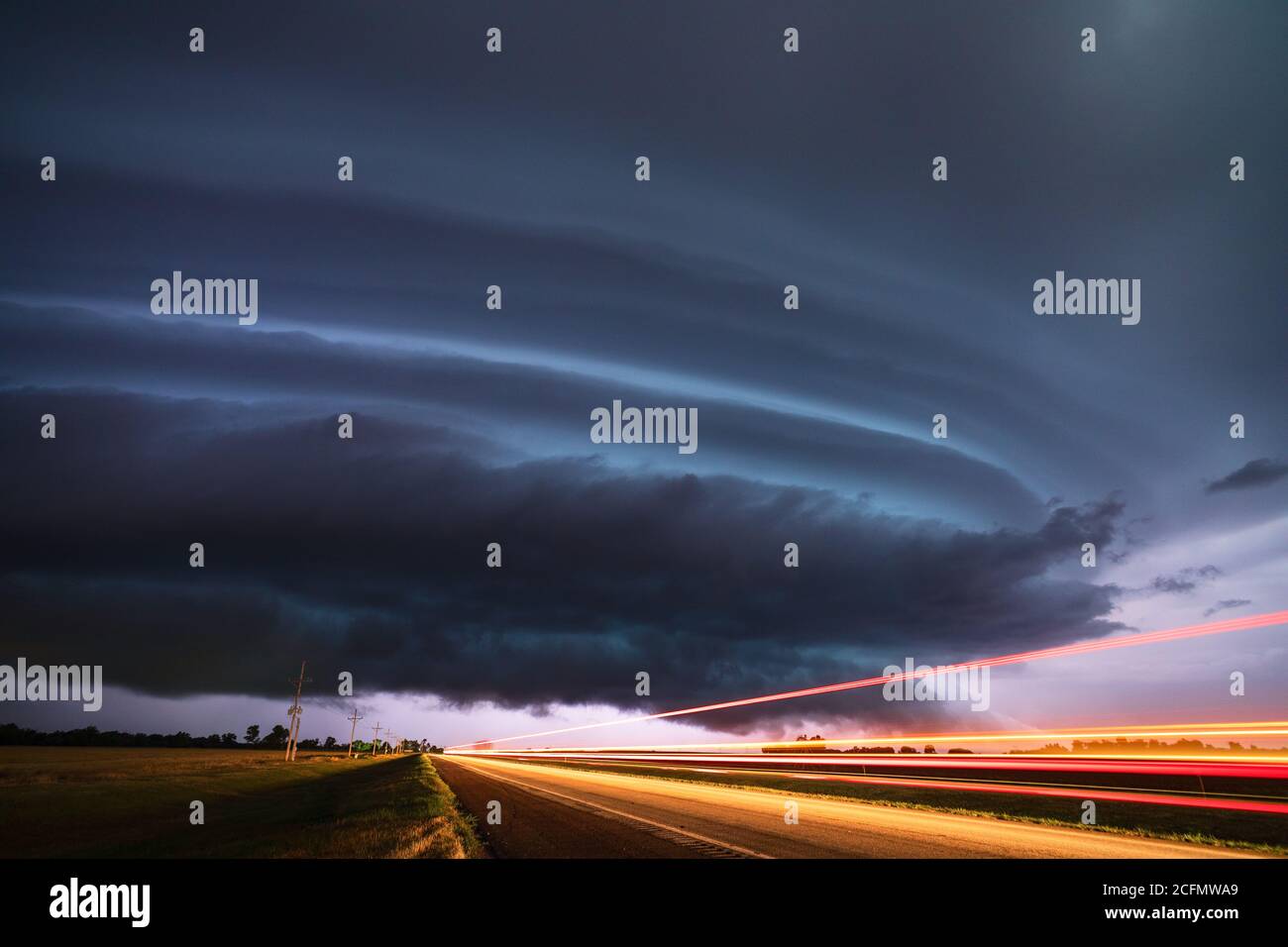 Supercell Gewitter und Straße mit dunklen, dramatischen Gewitterwolken, die von Blitzen in der Nähe von Ford, Kansas, beleuchtet werden Stockfoto