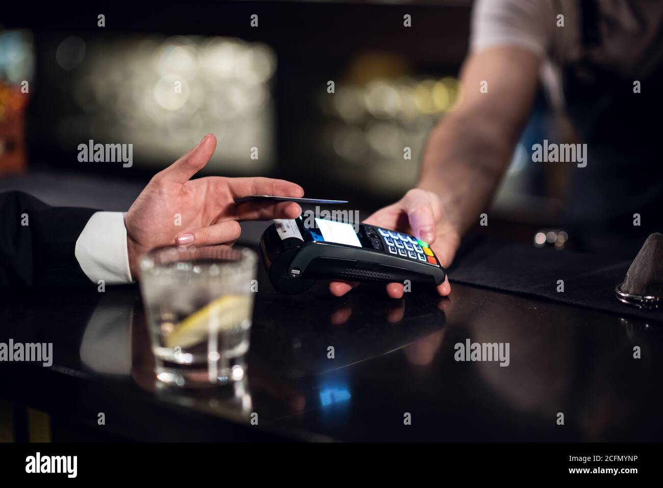 Der Mann bezahlt den Barkeeper für die Bestellung mit einer Kreditkarte. Stockfoto