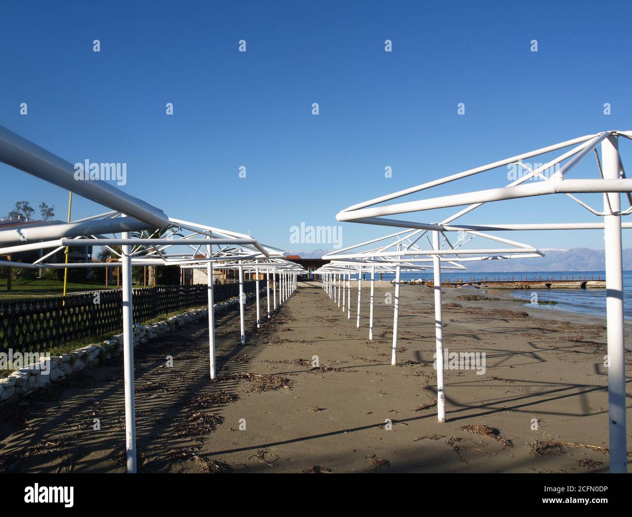 Ein Mann steht allein auf hölzernen Anlegesteg in den A Hotels, Roda Beach Hotel, Resort und Spa, Roda, Korfu, Griechenland im Winter Stockfoto