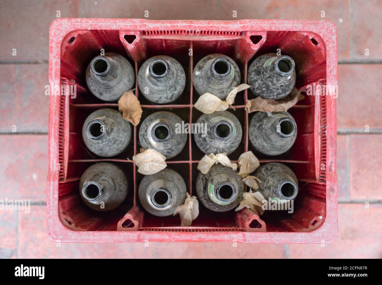 Draufsicht auf eine rote Box voller leerer Bierflaschen. Staubige Flaschen Stockfoto