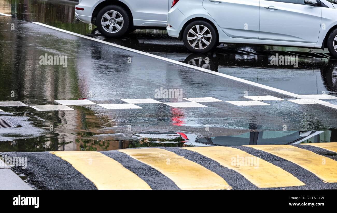 wolkiger Tag nach starkem Regen in der Stadt. Autos auf der Straße geparkt Stockfoto