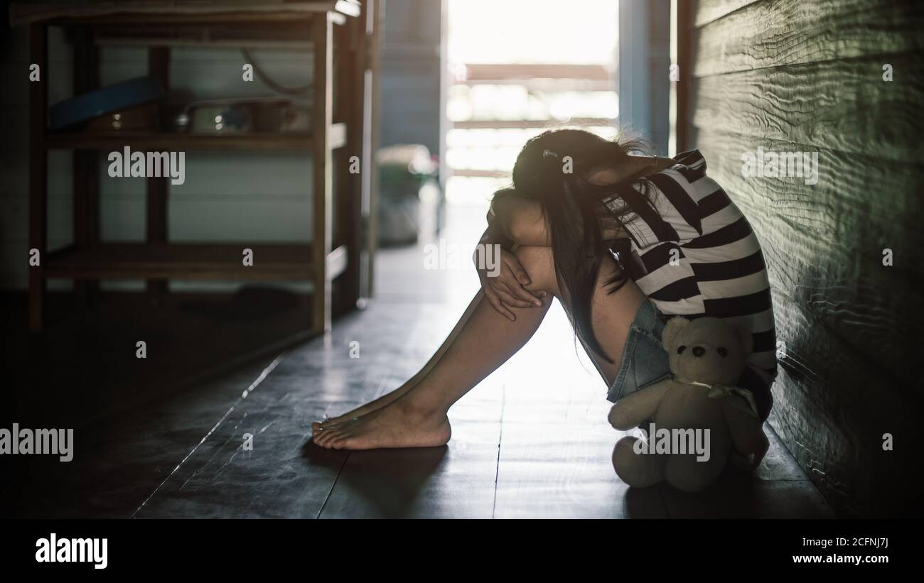 Kleines Kind Mädchen sitzt in der Nähe Teddybär mit einsamen und Traurigkeit.Low-Key-Stil Stockfoto