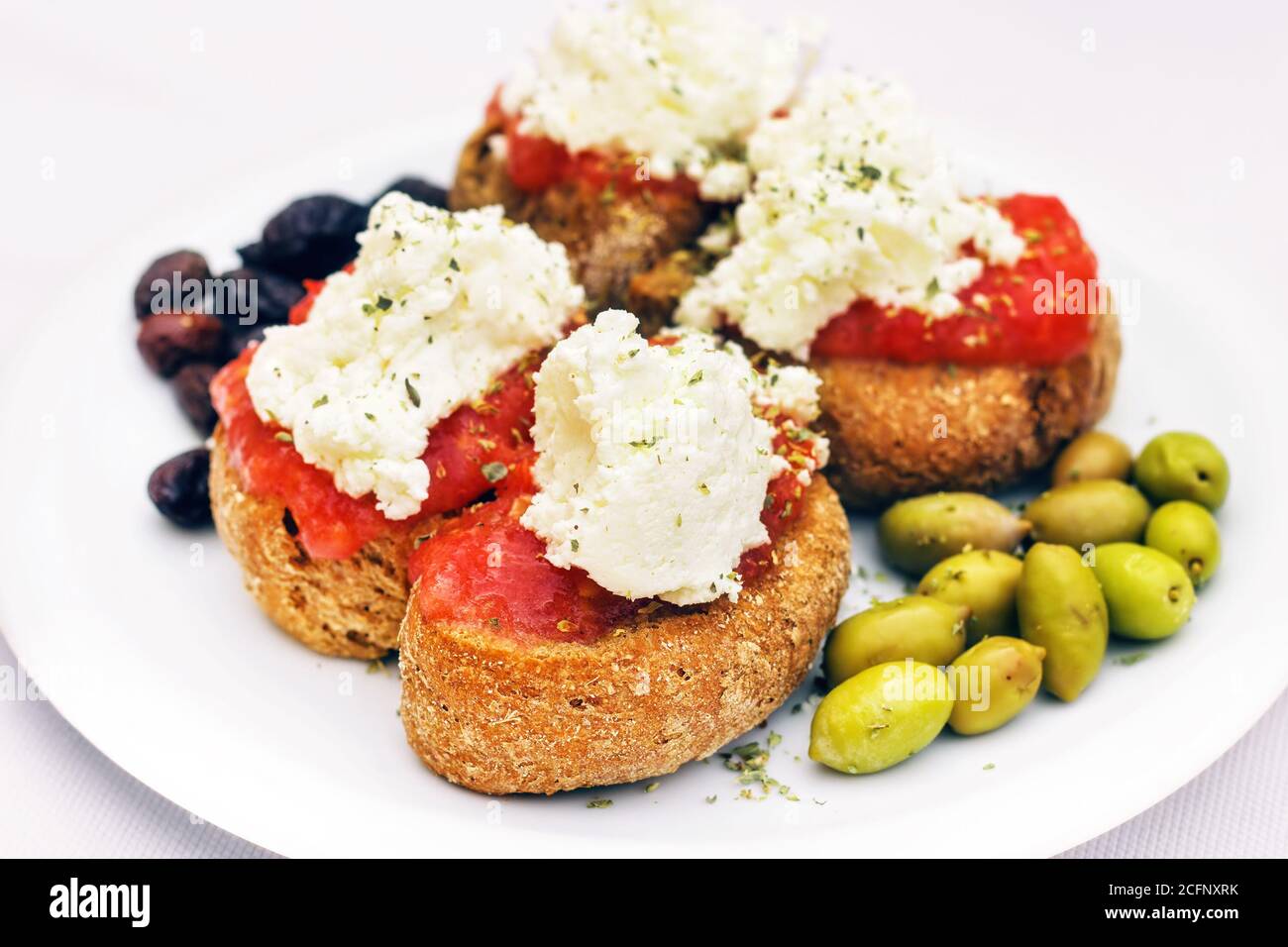 Kretische Vorspeise - Dakos, Zwieback mit Tomatensauce, Oliven und lokalem Staka-Käse (selektiver Fokus) Stockfoto