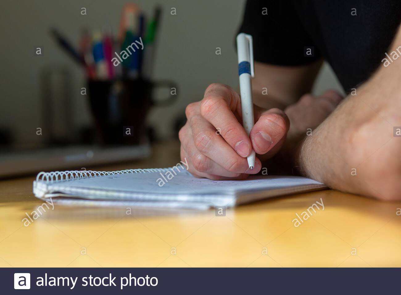 Ein junger Mann nimmt Notizen und berechnet, während er sitzt Ein Schreibtisch während einer Besprechung Stockfoto