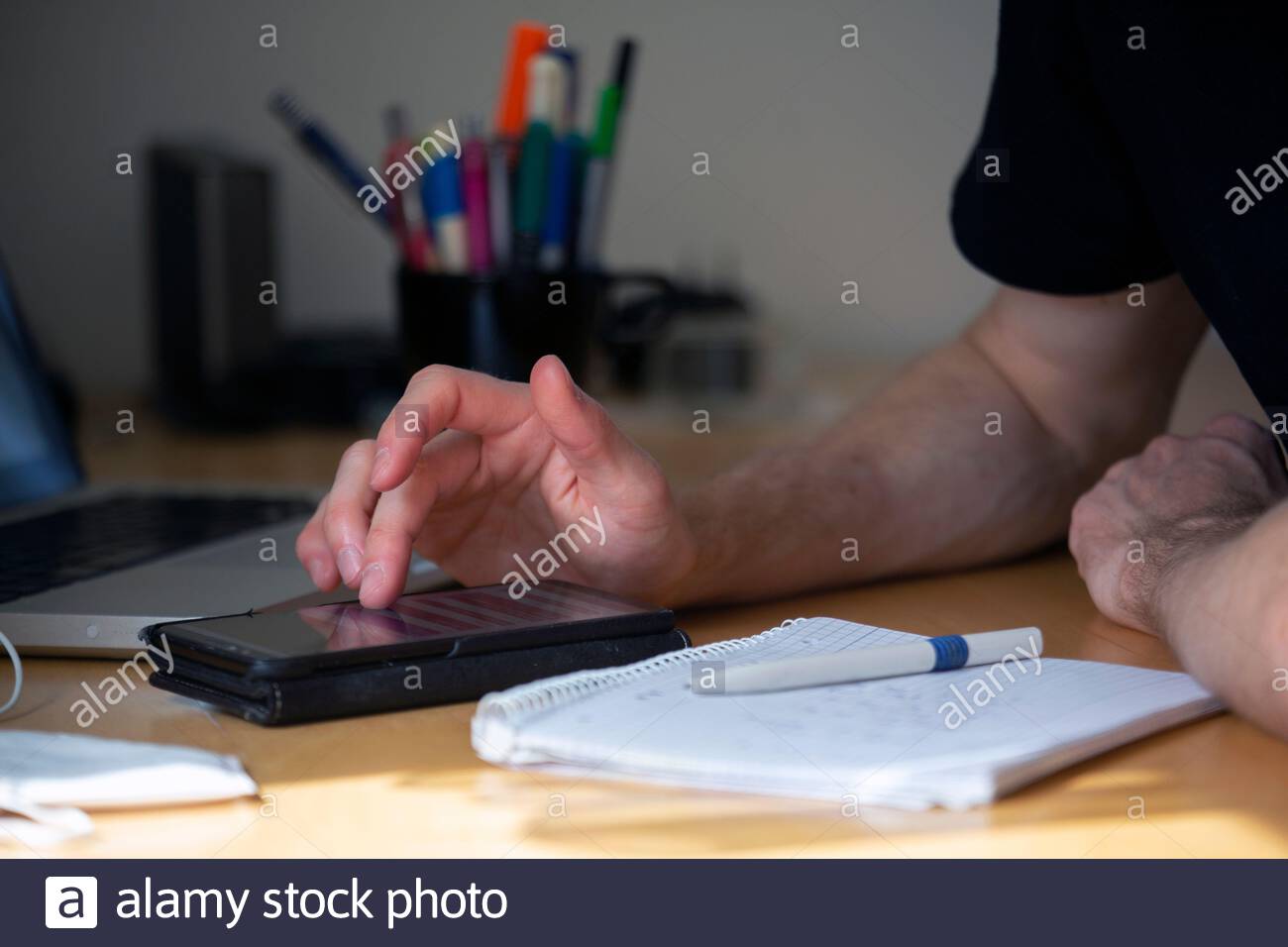 Ein junger Mann nimmt Notizen und berechnet, während er sitzt Ein Schreibtisch während einer Besprechung Stockfoto