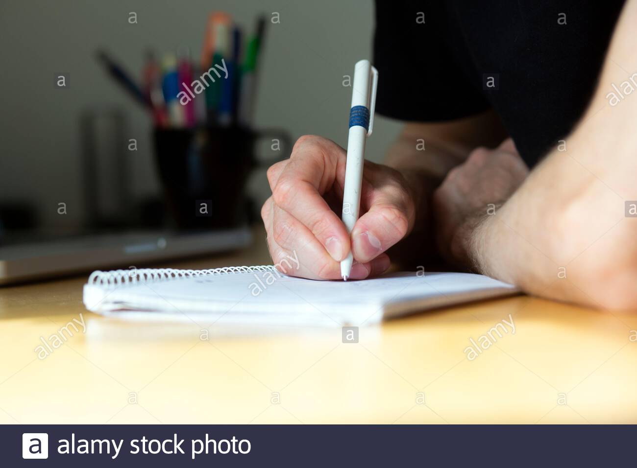 Ein junger Mann nimmt Notizen und berechnet, während er sitzt Ein Schreibtisch während einer Besprechung Stockfoto