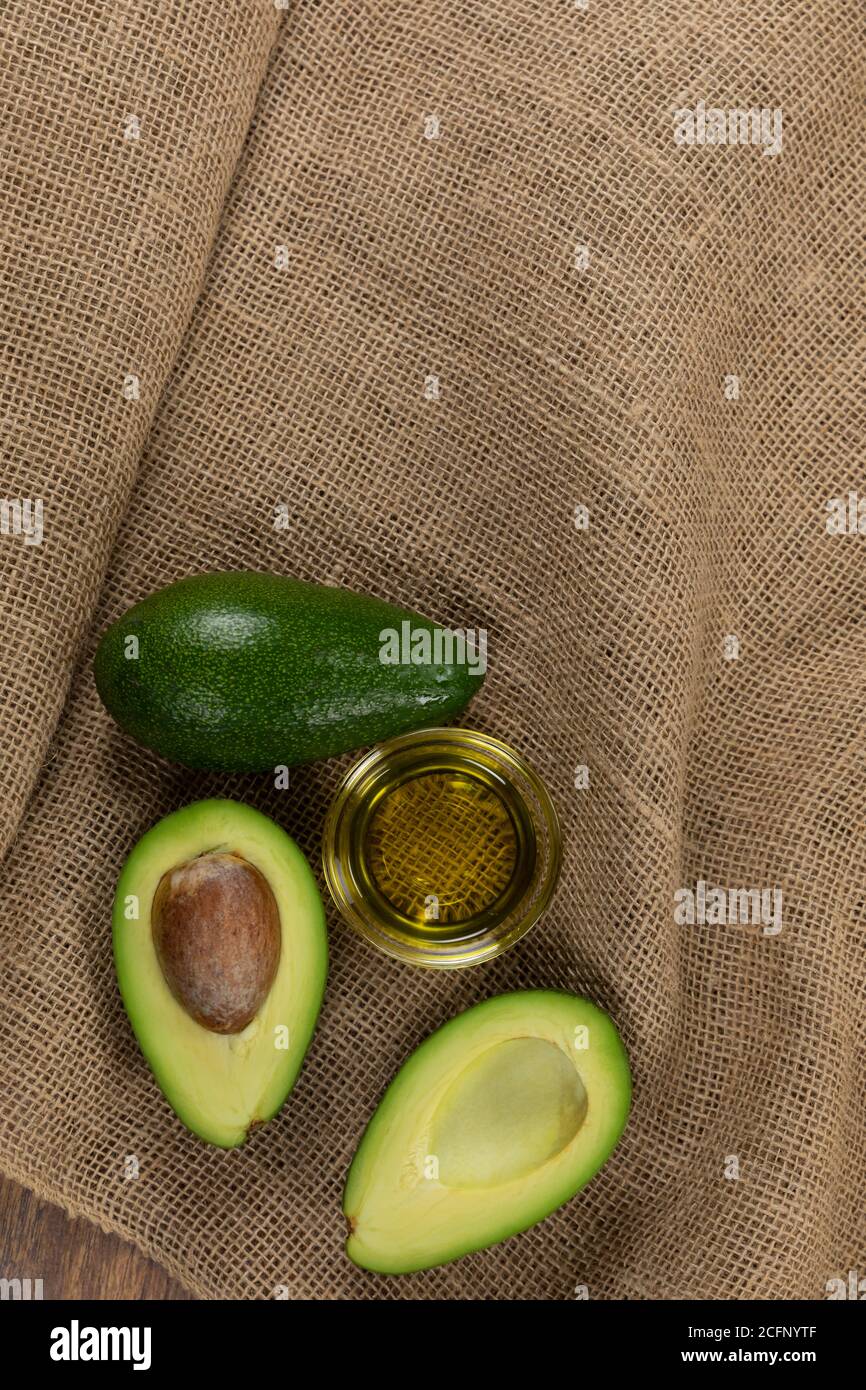 Blick auf zwei Avocados und Olivenölflasche auf Tuch Hintergrund Stockfoto