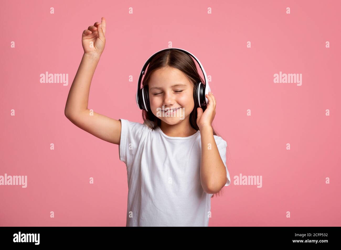 Musik und Spaß. Lächelndes kleines Mädchen in Kopfhörern genießen Lied Stockfoto