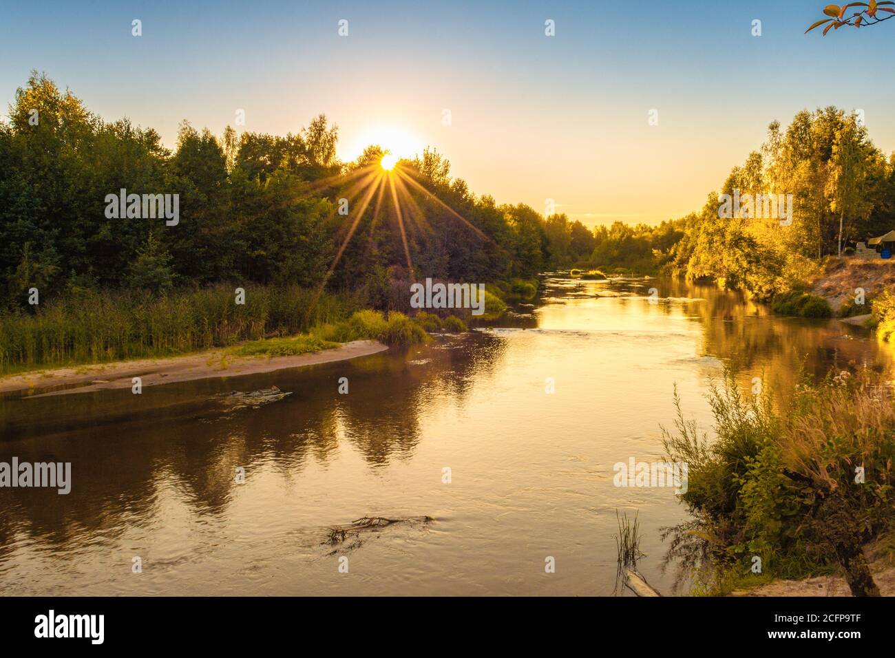 Kleiner Waldfluss bei Sonnenuntergang im Herbst. Schöne Landschaft, Sonnenuntergang auf dem Fluss. Goldener Sonnenuntergang am Fluss. Stockfoto