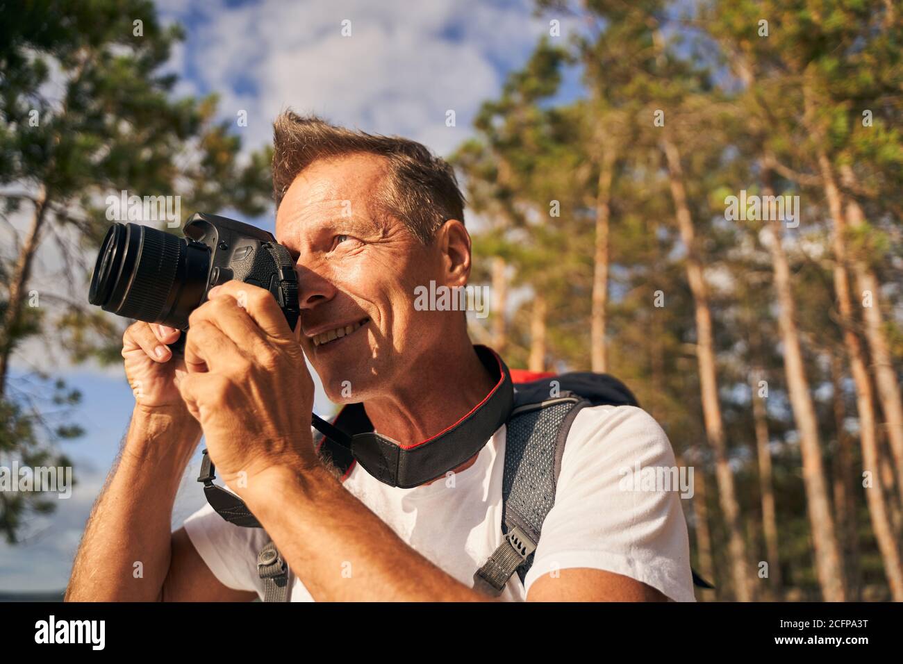 Lächelnder Mann mit Digitalkamera in der Natur Stockfoto